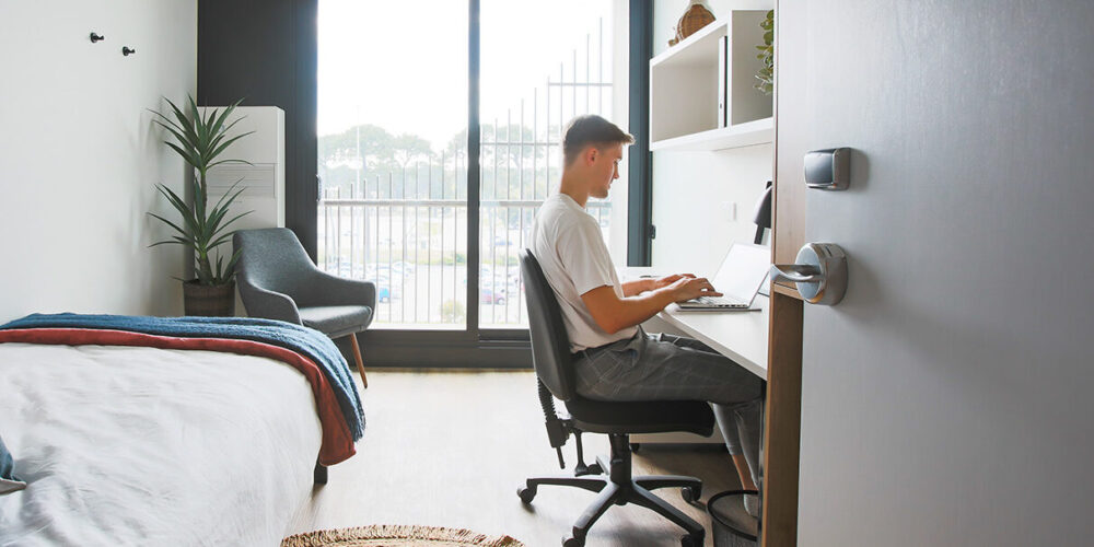 A man sitting at his desk and typing on his computer.