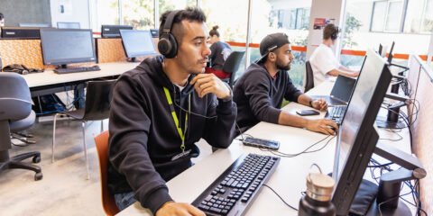 male student in one of the abacus rooms. wearing headphones and browsing the computer