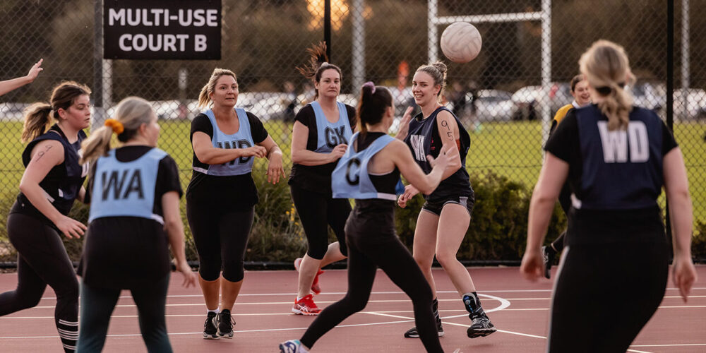 Netball team playing netball in an outdoor court