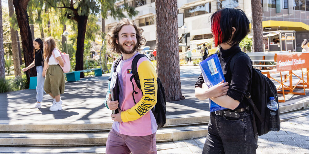 Two students walking and looking at each other - play video