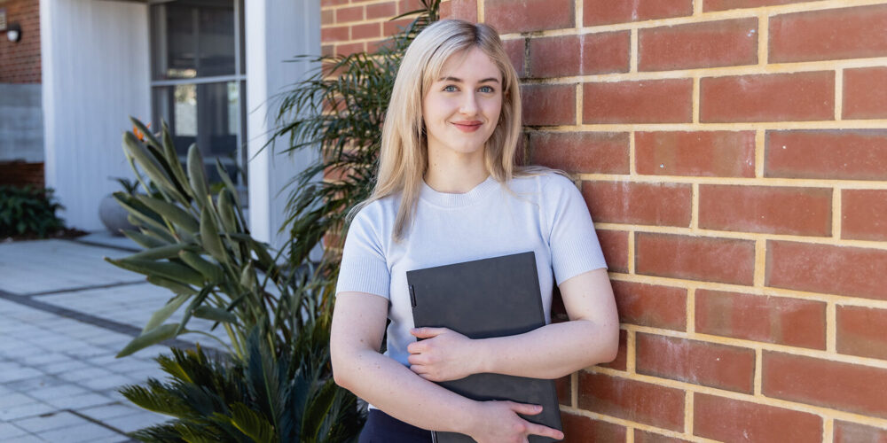 female student holding textbook and smiling