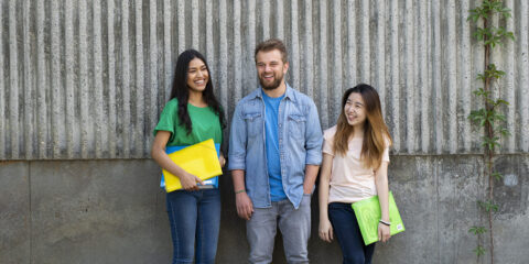 3 students against a wall and laughing