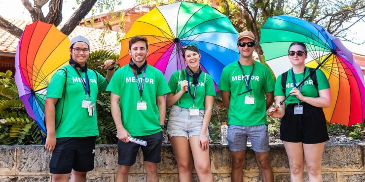 Five new to Curtin mentors standing with three rainbow umbrellas