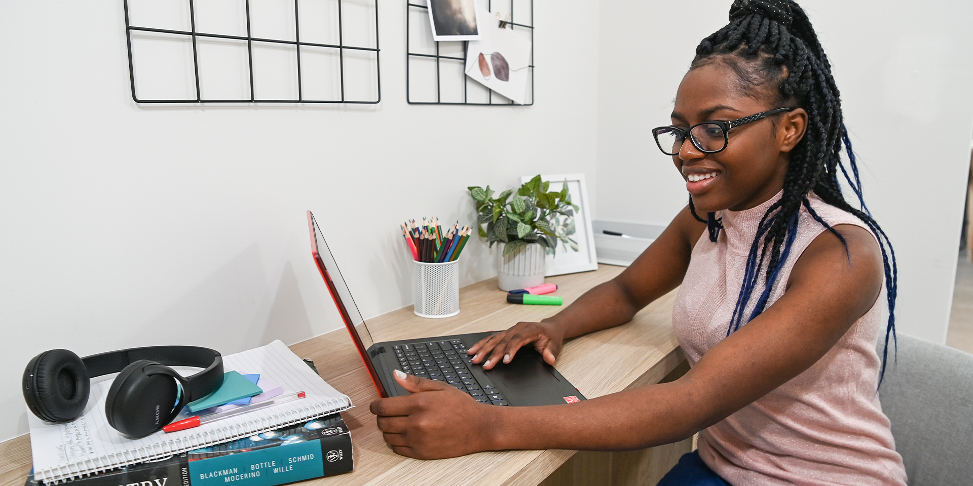 Female student sits at desk looking at her laptop screen