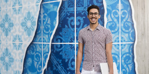 Person smiling at camera standing against wall