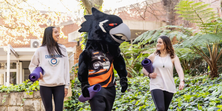 Two students walk down a path on campus with Carl the Carnaby.