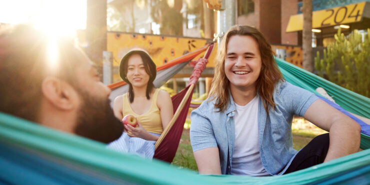 Three students relax on hammocks.